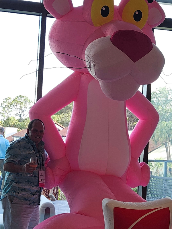 Ed Richards smiling and posing with the CEEE, Owens Corning Pink Panther mascot.