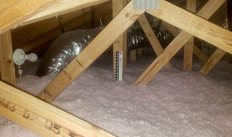 Leed Insulation R-38 blown-in fiberglass insulation installed in a residential attic alongside HVAC ductwork and roof trusses in Fort Pierce, FL.