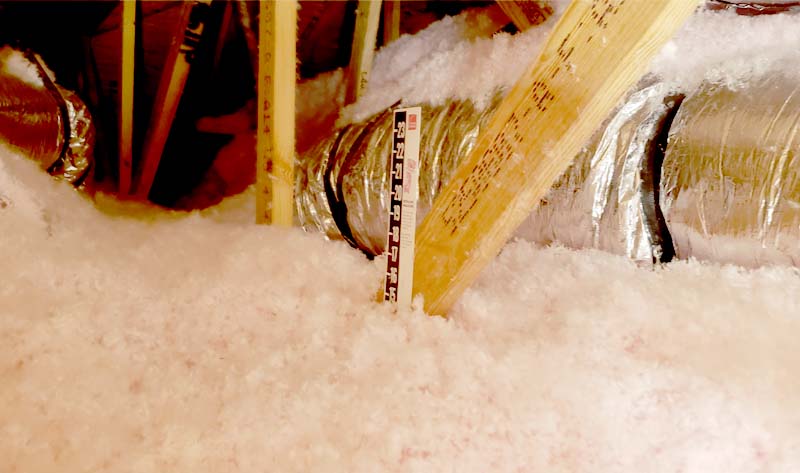 Leed Insulation R-38 blown-in fiberglass insulation filling a residential attic with depth ruler visible in Fort Pierce, FL.