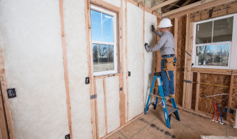 contractor installing fiberglass insulation in new home construction