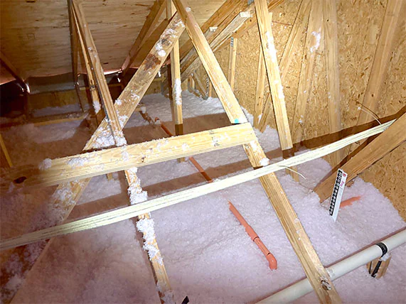 Blown-in fiberglass attic insulation with depth ruler.