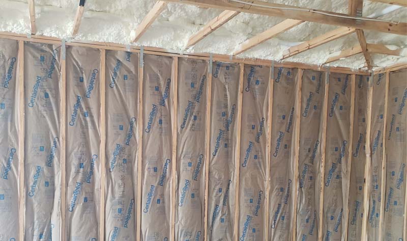 Leed Insulation CertainTeed kraft-faced fiberglass batt insulation installed in wall studs with open-cell spray foam along the roofline in Fort Pierce, FL.